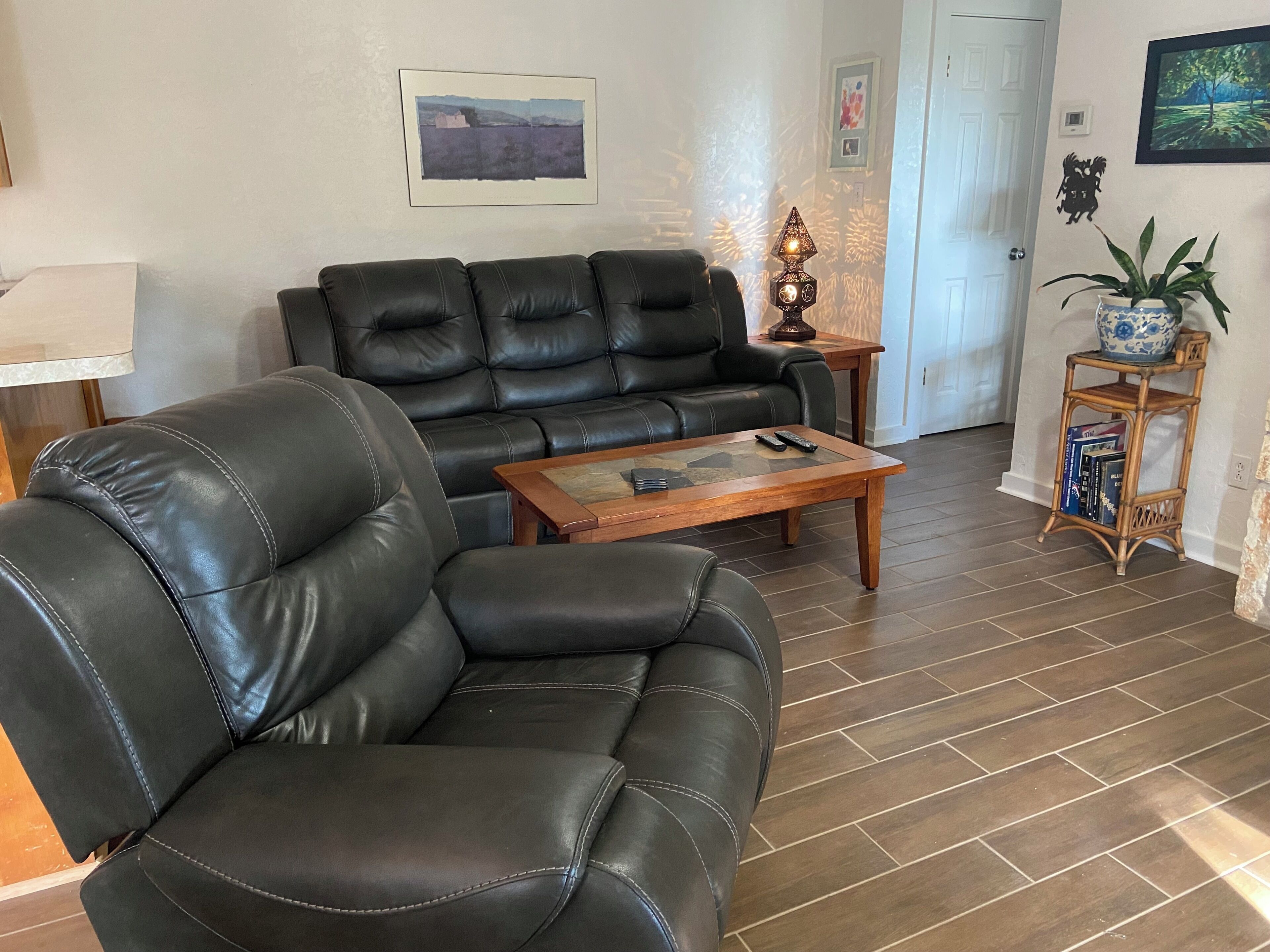A living room with a black leather sofa, a wooden coffee table, and a small side table with a lamp.