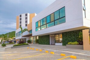 A modern building with a flat facade, large windows, and a landscaped area with plants. - Coralina Suites: ¡Tu Refugio en Santa Marta! (Santa Marta)