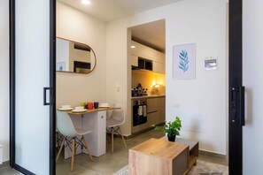 A compact living space with a kitchenette, a dining area with a small table and chairs, and a single potted plant. - Coralina Suites: ¡Tu Refugio en Santa Marta! (Santa Marta)