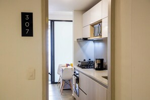 A modern kitchen with a stove, coffee maker, and a dining area with a table and chairs. - Coralina Suites: ¡Tu Refugio en Santa Marta! (Santa Marta)
