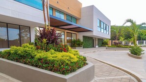 Un bâtiment moderne doté d’une cour aménagée, de grandes fenêtres et d’une galerie couverte.