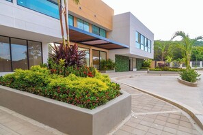 A modern building with a landscaped courtyard, large windows, and a covered walkway. - Coralina Suites: ¡Tu Refugio en Santa Marta! (Santa Marta)