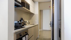 Une cuisine compacte équipée d’une cuisinière, d’un four à micro-ondes et d’un four traditionnel, d’un petit plan de travail et d’une porte donnant sur une autre pièce.
