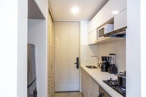 A compact kitchen with a microwave, coffee maker, and stove. - Estudio Boutique con Balcon Vista y Parqueo (Santa Marta)