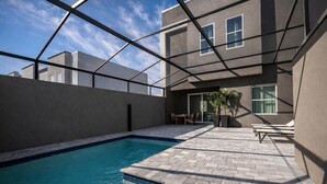 A swimming pool with a clear blue water surface, surrounded by a paved patio area with a geometric pattern. - Kissimmee Villa 5BR Private Pool (Davenport)