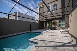 Ein Schwimmbecken mit glasklarer, blauer Wasseroberfläche, umgeben von einer gepflasterten Terrasse mit geometrischem Muster.