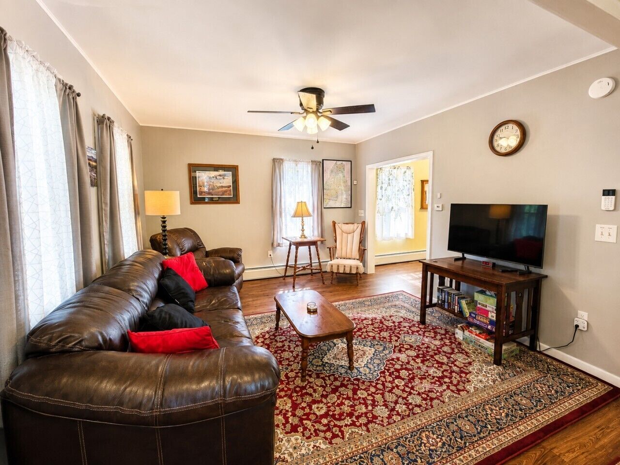 A living room with a leather sofa, a coffee table, a television, and a patterned rug.