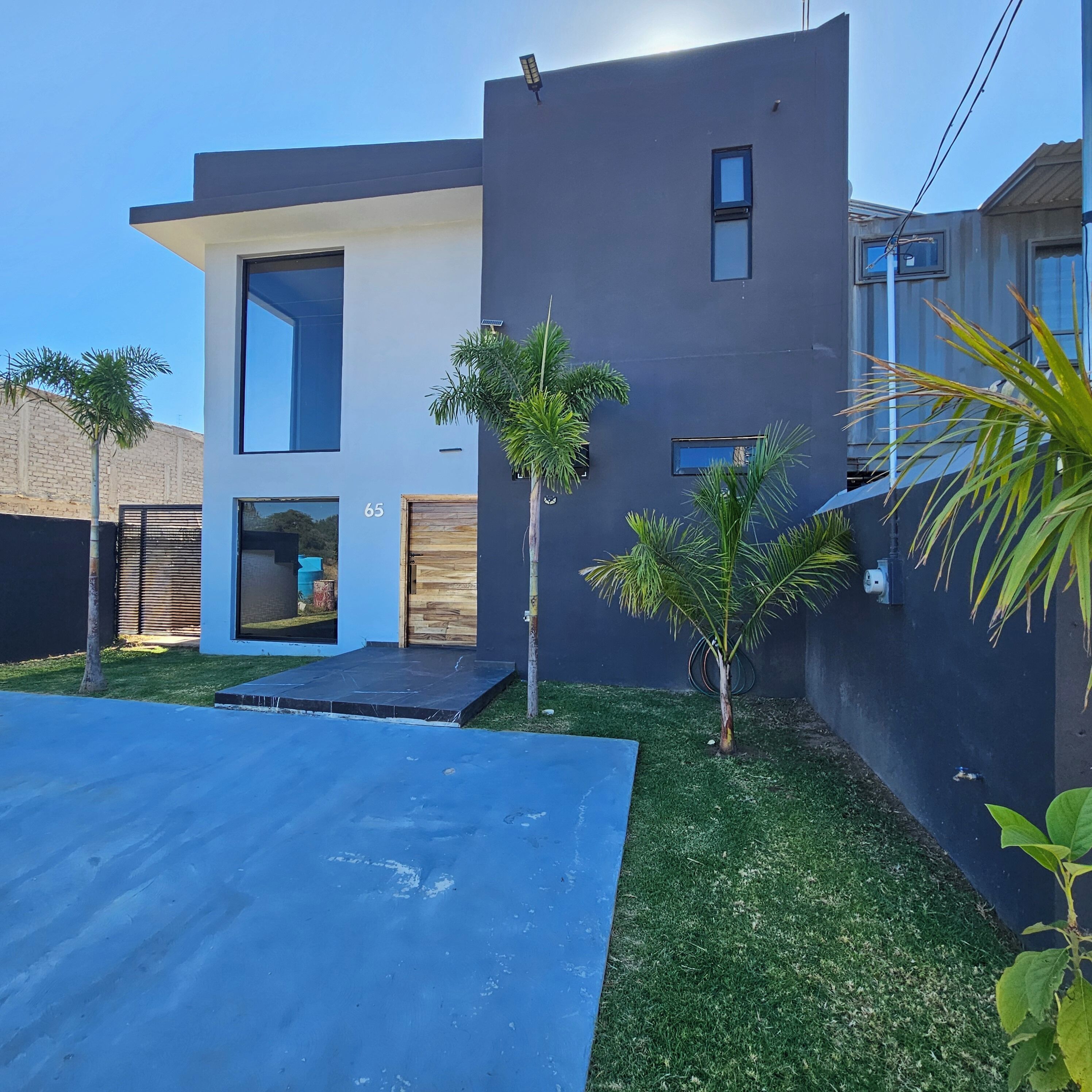 Una casa moderna de dos pisos con techo plano, un ventanal grande y una puerta.