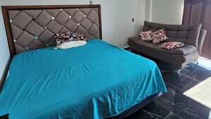 A bedroom with a bed, a sofa, and a ceiling fan.