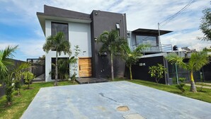 Una casa moderna de dos pisos con techo plano, un porche delantero y entrada pavimentada.