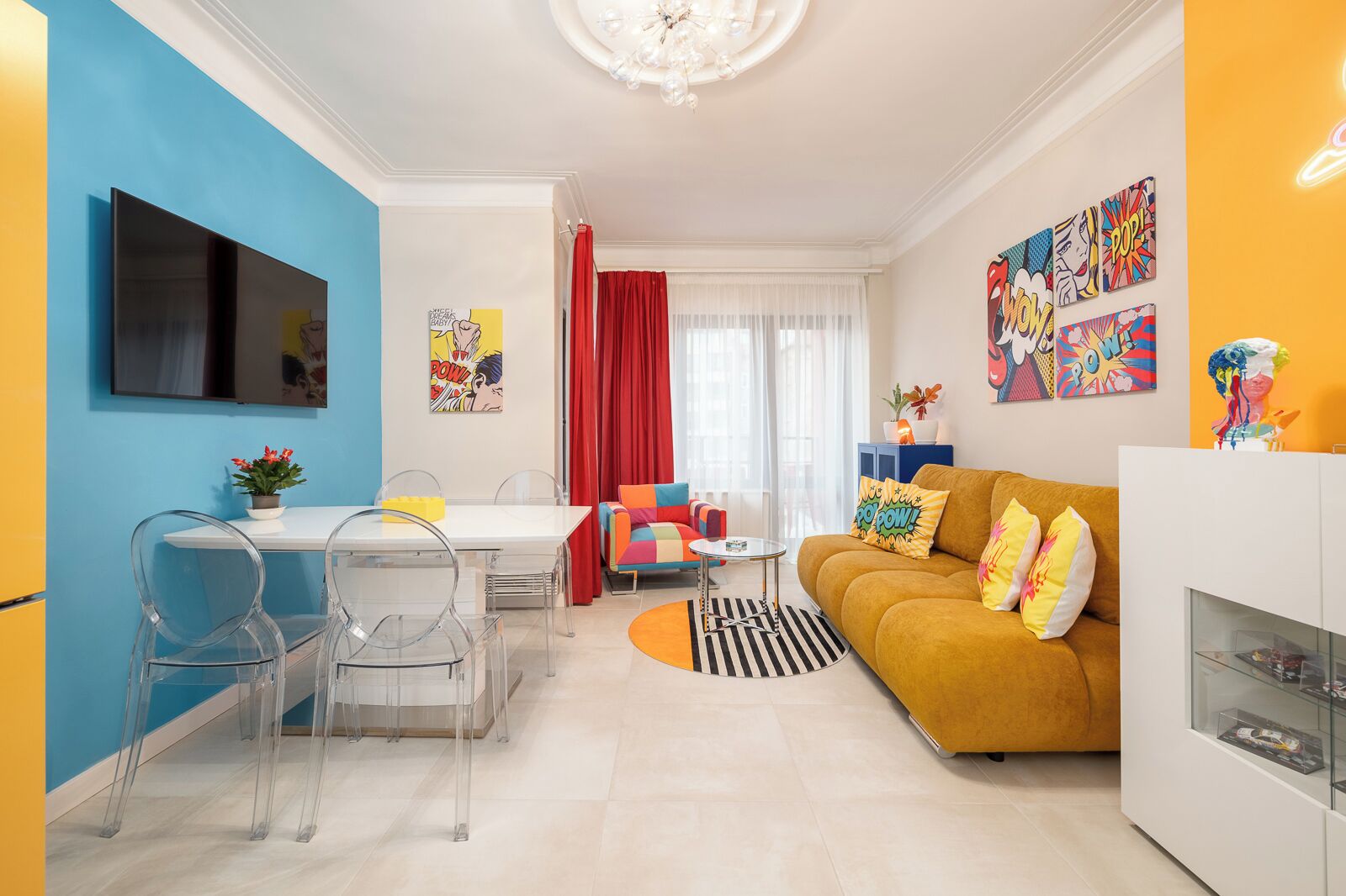Una sala de estar moderna con un sofá, una mesa de comedor con sillas y un televisor montado en la pared.