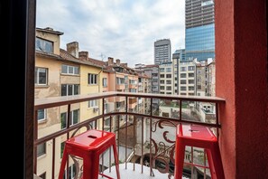 En balkong med utsikt över en stadsbild, inklusive bostadshus och en hög kontorsbyggnad.