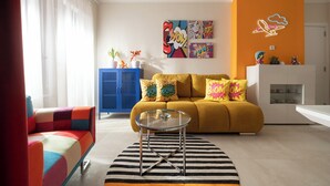 A modern living room with a sofa, a coffee table, and colorful cushions. There is a blue cabinet and a white cabinet with decorative items on top. - Pop-Art Apartment Sofia I 9 people I 3 Bedrooms I 3 Bathrooms I Design awarded (Sofia)