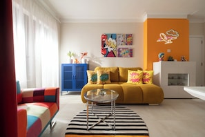 A modern living room with a sofa, a coffee table, and colorful cushions. There is a blue cabinet and a white cabinet with decorative items on top. - Pop-Art Apartment Sofia I 9 people I 3 Bedrooms I 3 Bathrooms I Design awarded (Sofia)