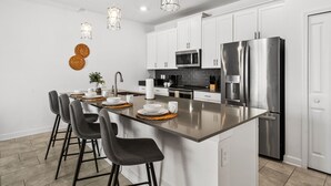 A modern kitchen with a central island, stainless steel appliances, and pendant lighting. - Sleeps 10 *Private Pool *FREE Waterpark Access! (Kissimmee)