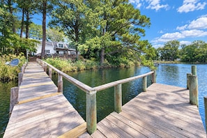 A wooden dock extending into a calm body of water, surrounded by lush greenery and trees.
