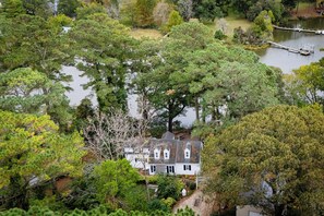 A house surrounded by dense trees and a body of water.