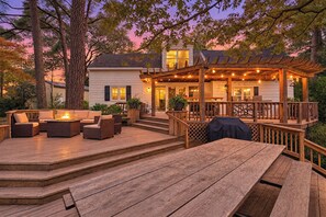 A wooden deck with outdoor furniture, a barbecue grill, and a covered patio area.