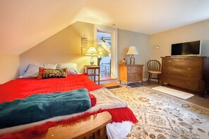 A bedroom with a bed, a dresser, a chair, a television, and a lamp.