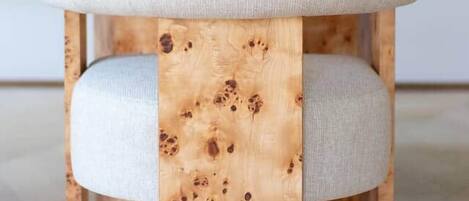 Un taburete de madera con asientos acolchados y un cuadro al fondo.