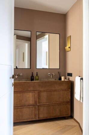A modern bathroom with a wooden vanity, two mirrors, and a wall-mounted light fixture. - Príncipe Executive Residence (Madrid)