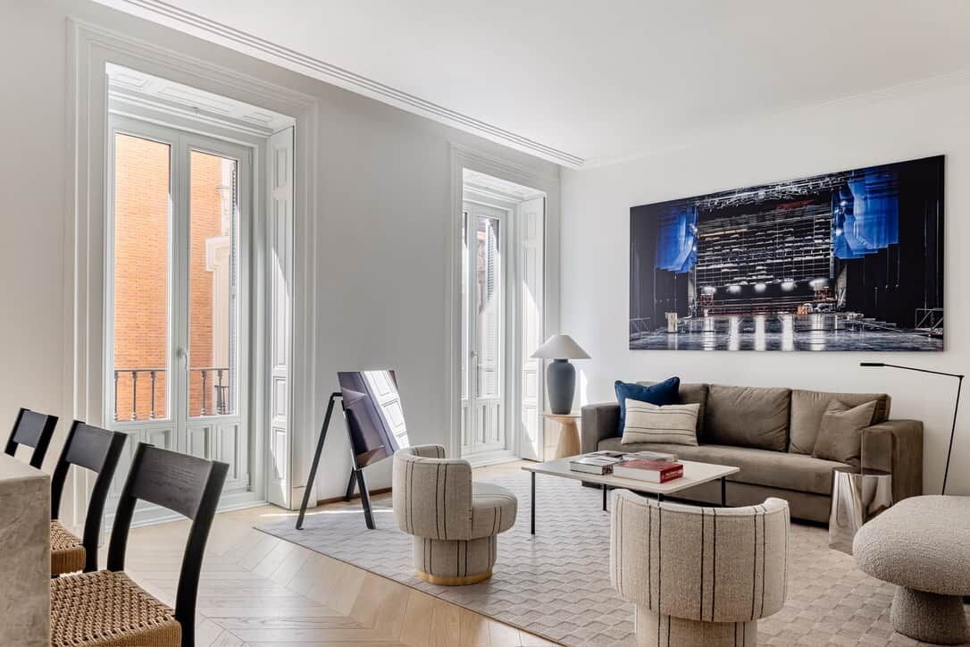 Un salon moderne avec un grand tableau, un canapé, une table basse et un fauteuil.
