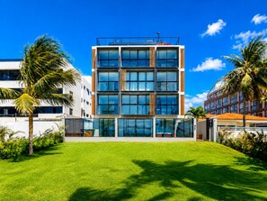A modern multi-story building with a flat roof, large windows, and a well-maintained lawn. - Breeze Residence 401 Beachfront Flat at Bessa (João Pessoa)
