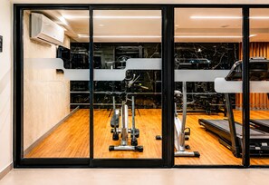 Ein Fitnessraum mit Trainingsgeräten, Laufband und einer Spiegelwand.