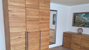 A room with a large wooden wardrobe, a smaller dresser, a mirror, and a painting on the wall. - Lovingly renovated farmhouse for 2–6 adults (+ 2 children) in a quiet location (Reisbach)