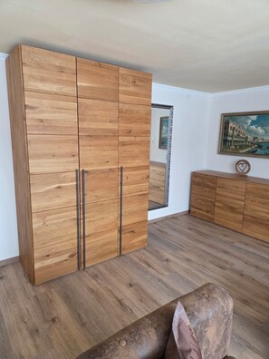 Ein Zimmer mit einem großen Holzschrank, einer kleinen Kommode, einem Spiegel und einem Gemälde an der Wand.