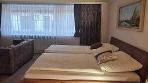 A hotel room with two beds, a sofa, and a large window with sheer curtains. - Lovingly renovated farmhouse for 2–6 adults (+ 2 children) in a quiet location (Reisbach)