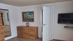 A living room with a sofa, a wooden coffee table, a dresser, a painting on the wall, and a television. - Lovingly renovated farmhouse for 2–6 adults (+ 2 children) in a quiet location (Reisbach)