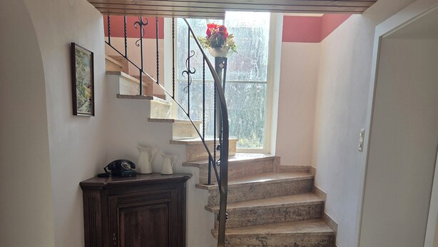 A staircase with a wooden handrail and a small window at the top. - Lovingly renovated farmhouse for 2–6 adults (+ 2 children) in a quiet location (Reisbach)