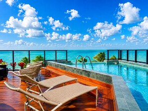 Ein Poolbereich mit Liegestühlen und Blick auf den Ozean.