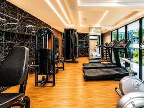 Un gimnasio con equipo de ejercicio, suelo de madera y ventanas grandes.