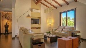 Ein modernes Wohnzimmer mit Sofa, Couchtisch, Hocker und Fernseher.