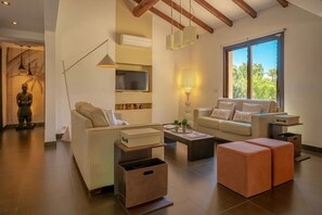 Ein modernes Wohnzimmer mit Sofa, Couchtisch, Hocker und Fernseher.