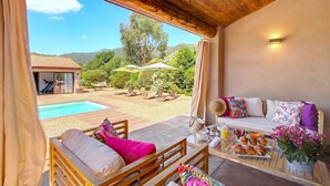 Ein Zimmer mit Blick auf einen Pool, Außenmöbel und einer Frühstücksecke.