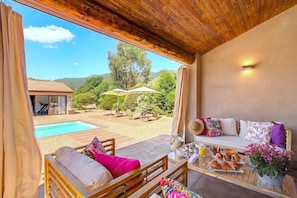 Ein Zimmer mit Blick auf einen Pool, Außenmöbel und einer Frühstücksecke.