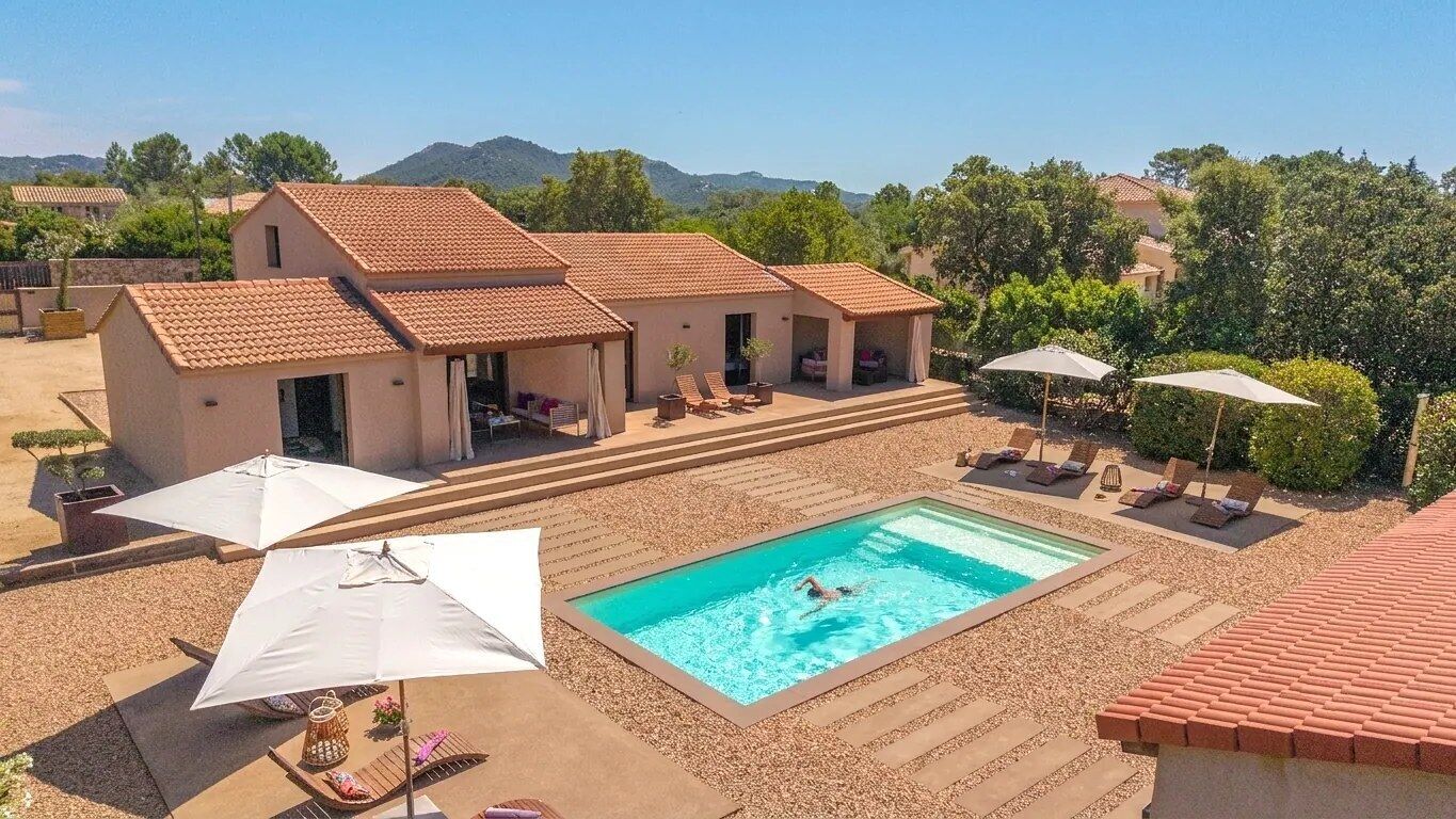 A residential property with a swimming pool, outdoor seating, and a view of the surrounding landscape.