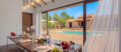 A dining area with a view of a swimming pool and a building.