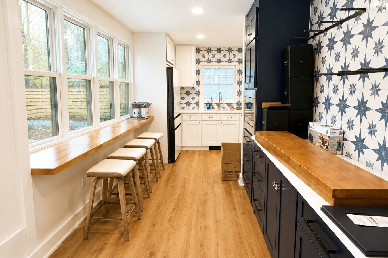 A kitchen with a wooden countertop, bar stools, a refrigerator, and a backsplash with star patterns.