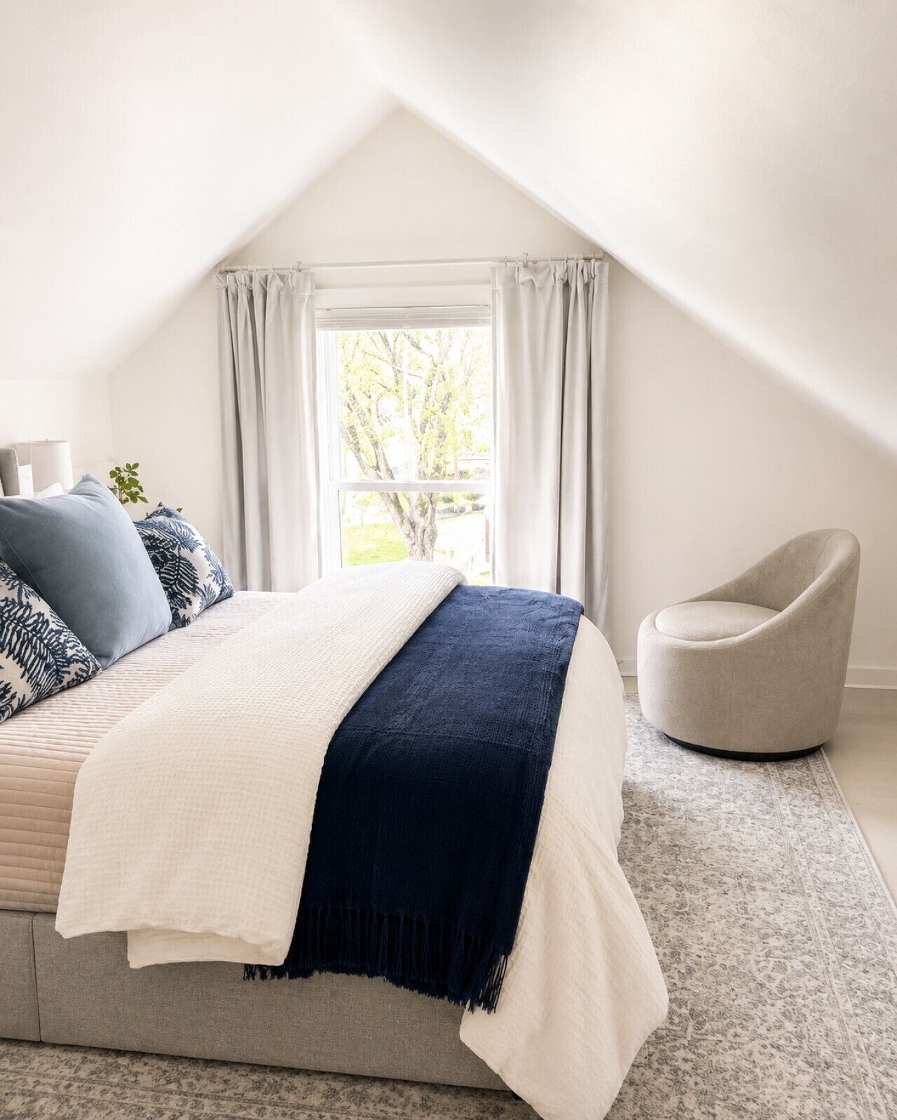 A bedroom with a bed, a chair, a window, and a view of the outdoors.