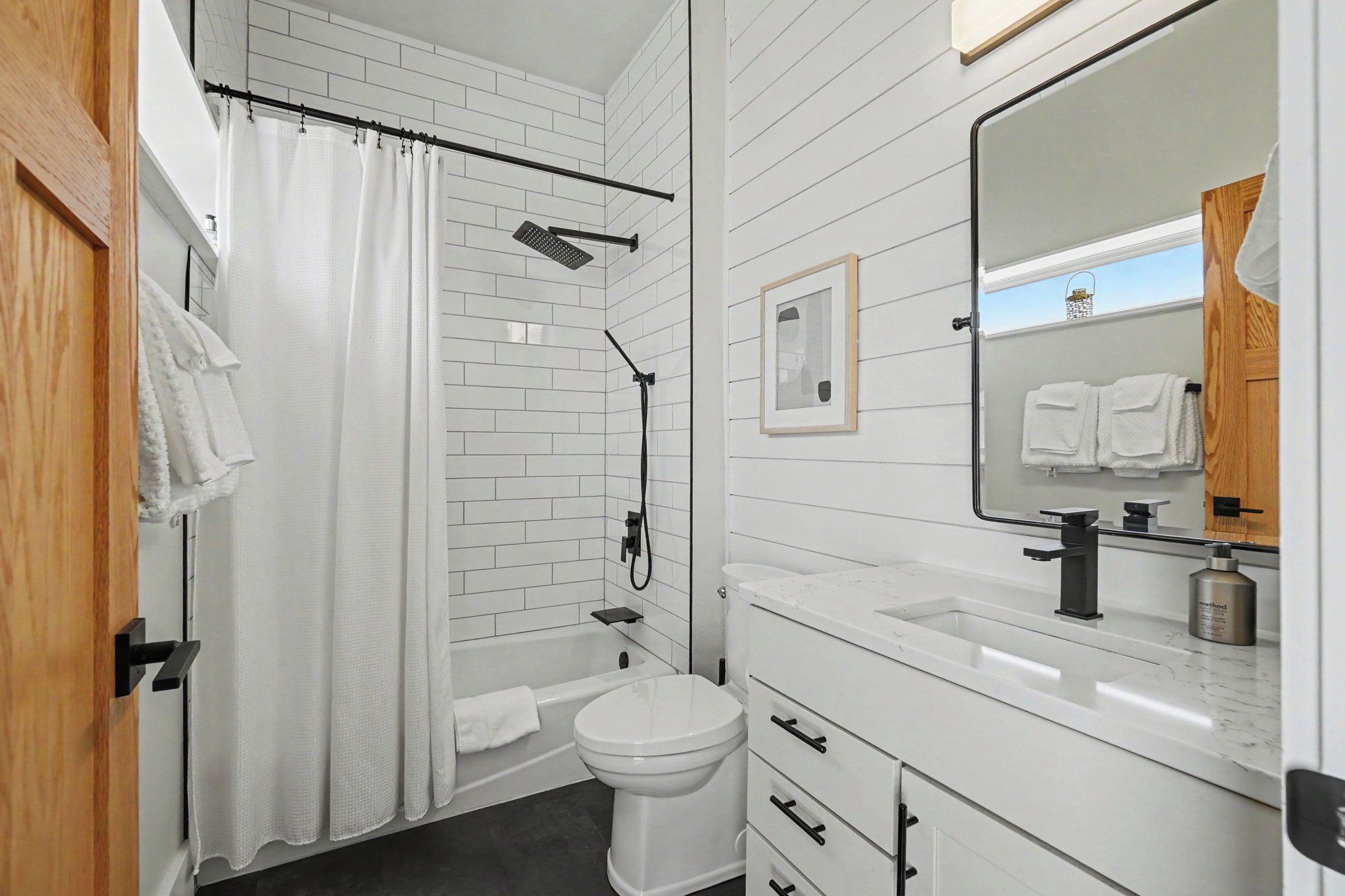 Une salle de bain équipée d’une douche, de toilettes, d’un lavabo et d’un miroir.