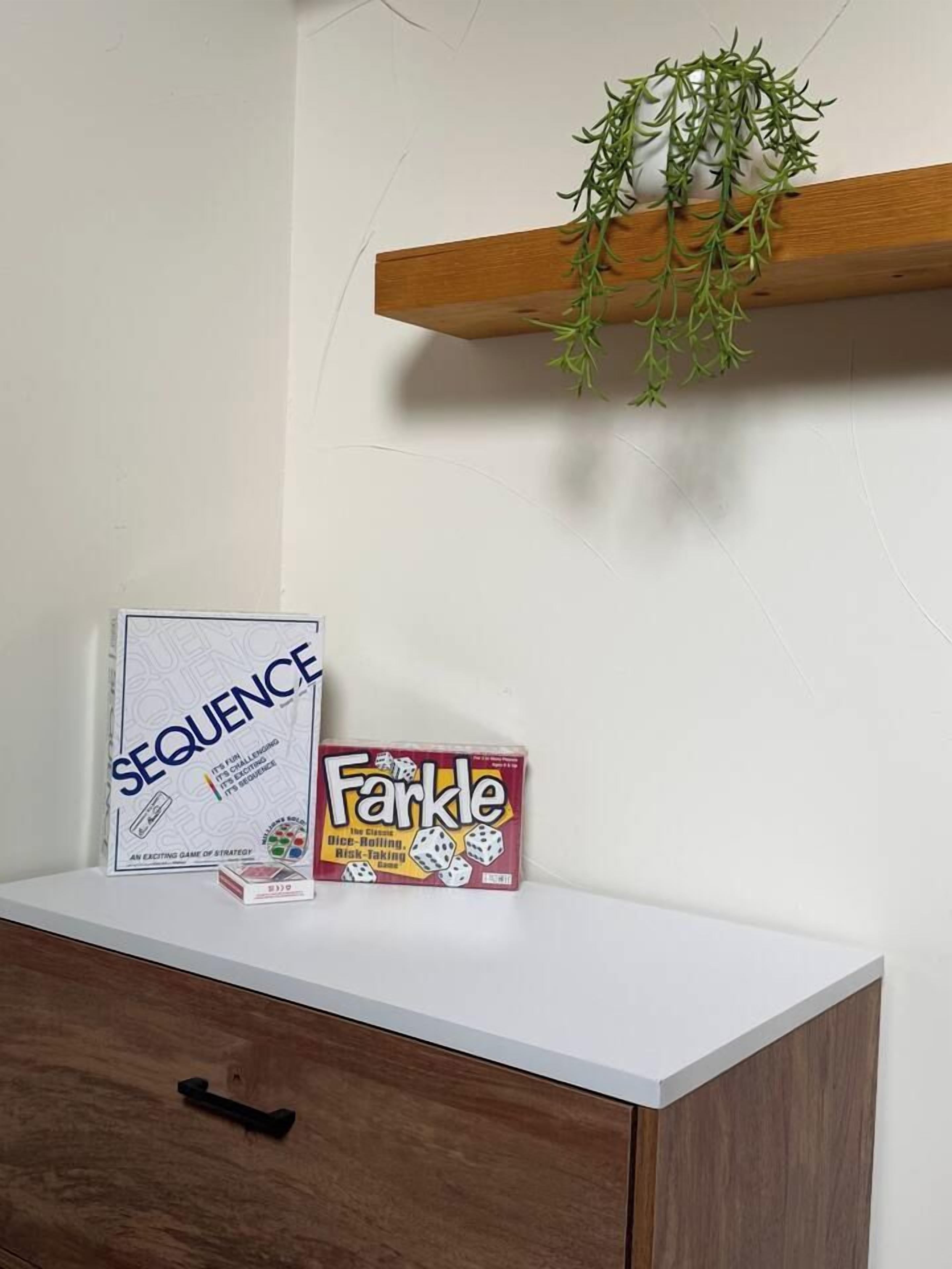 Ein weißer Tisch mit einer Spielbox mit dem Aufdruck 'Sequence' und einer Spielbox mit dem Aufdruck 'Farkle'.