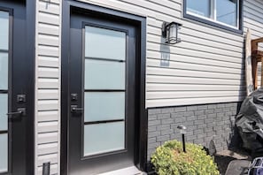 A modern house with a black front door, a garage door, and a small garden area with a potted plant.