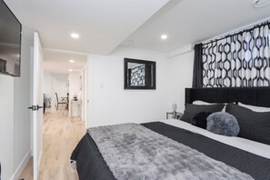 A modern bedroom with a large bed, a headboard, and a wall-mounted TV.