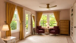 Ein Schlafzimmer mit einem Bett, zwei Sesseln, einem kleinen Tisch, einer Kommode und einem Deckenventilator.
