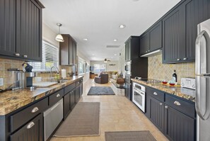 A modern kitchen with dark cabinetry, granite countertops, and stainless steel appliances.