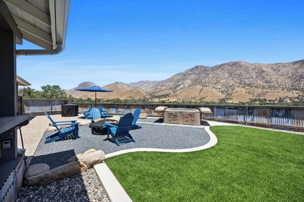 A patio with outdoor furniture, a stone fire pit, and a view of mountains and a body of water.